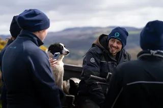 Farmers talking outdoors with a sheepdog